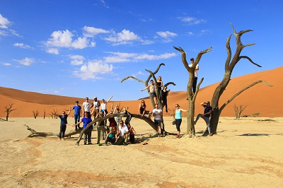 people balance on dead tree namib desert deadvlei